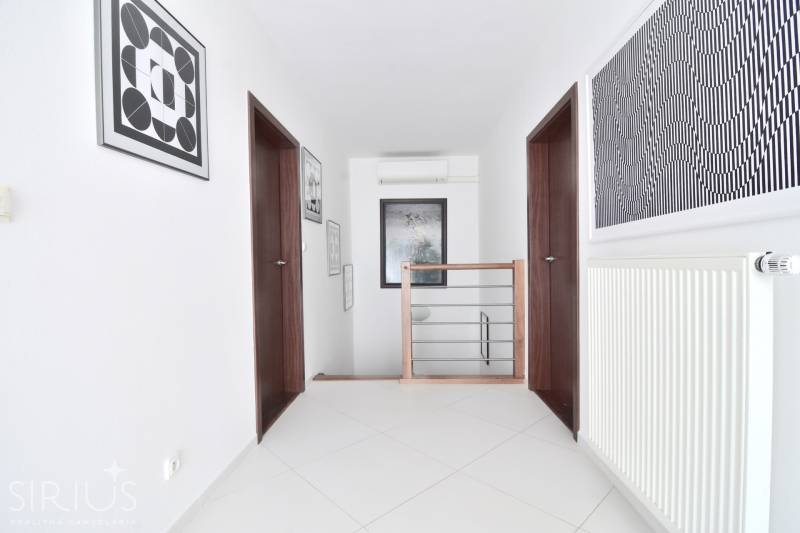 A hallway in a 4-room apartment with a staircase, paintings, and a radiator on the wall.