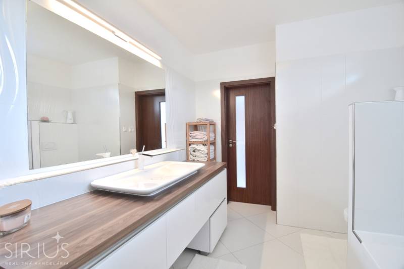 Bathroom in a 4-room apartment with a wooden cabinet, sink, and large mirror.