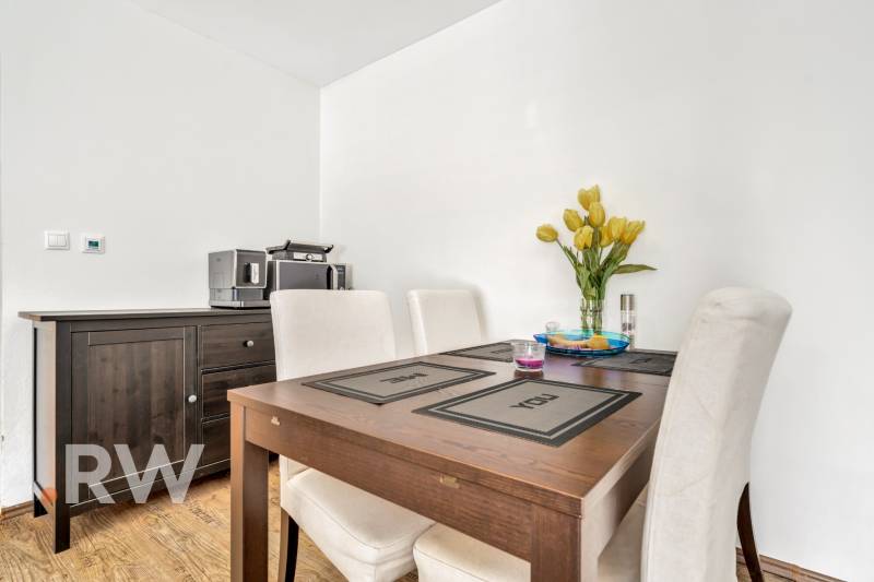 Dining area with a table and chairs in a 3-room apartment, a vase with flowers on the table.