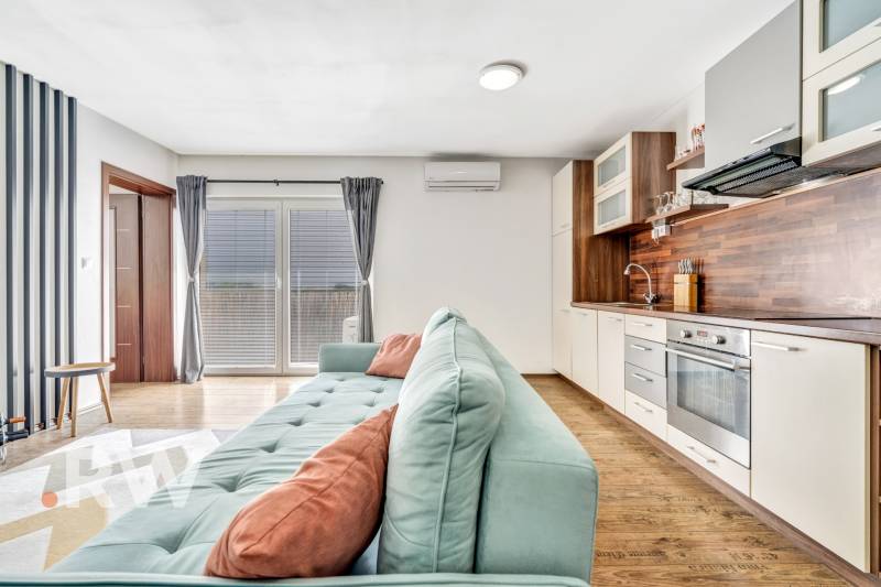 Living room with kitchen in a 3-room apartment, light sofa, wooden floor.