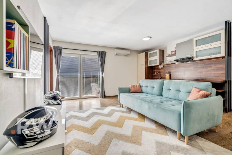 Living room in a 3-room apartment with a sofa and access to the terrace.
