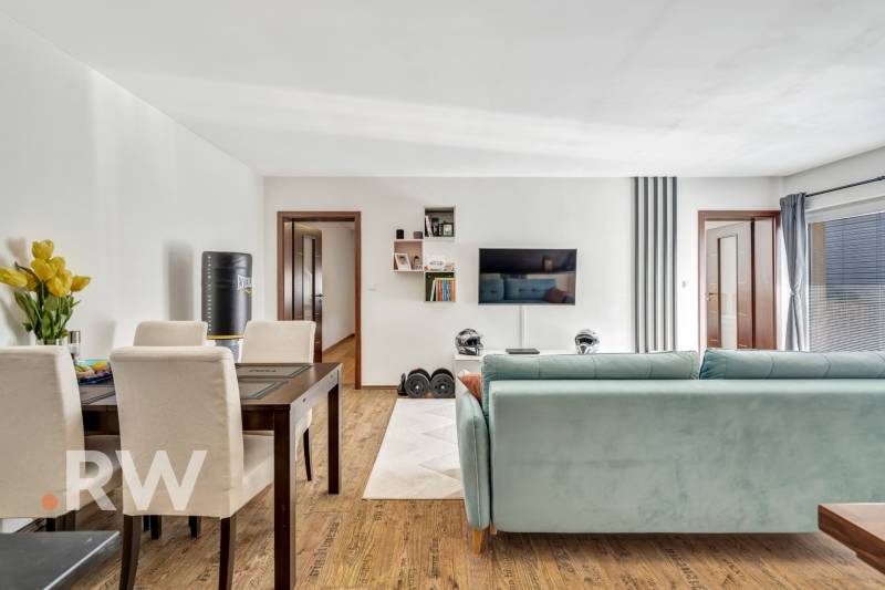 Living room in a 3-room apartment with a sofa, dining table, and a TV on the wall.