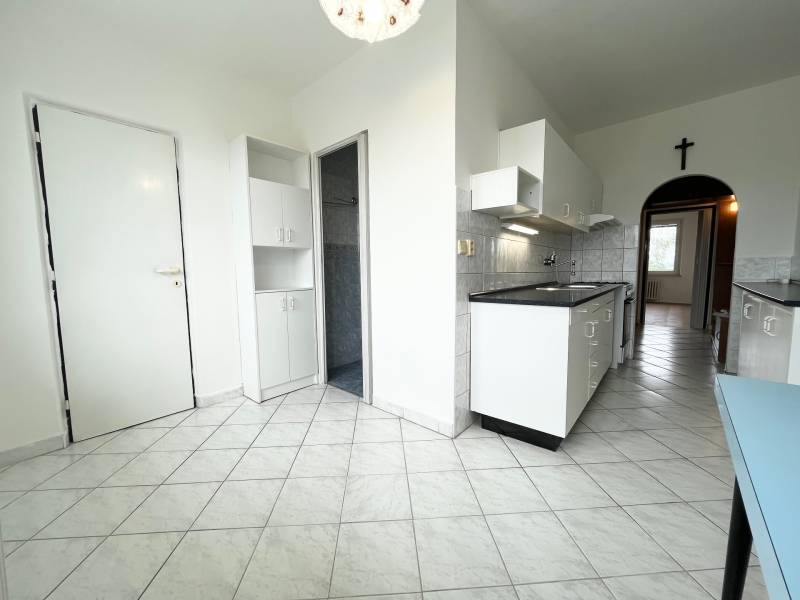 A kitchen with white cabinets and tiles in a 2-room apartment, a bright and spacious area.