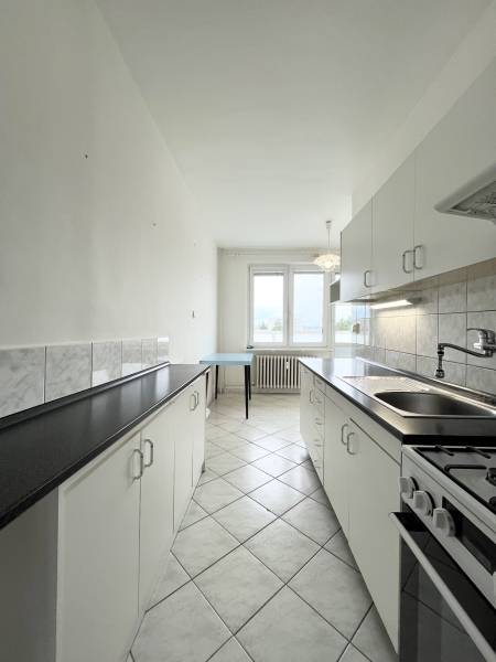 The kitchen in a 2-room apartment with white cabinets and black countertops.