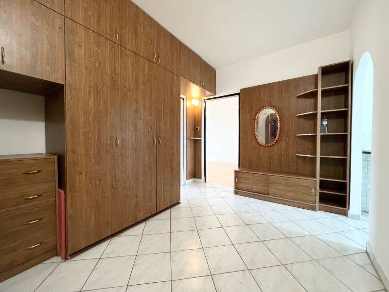 Interior of a 2-room apartment with wooden cabinets and a mirror on white tiles.