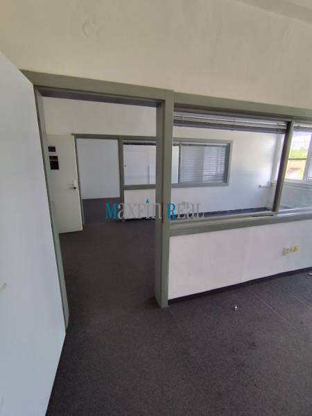 Offices with glass partitions and carpet, entrance through open doors.