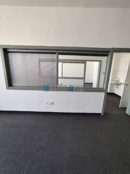 An office interior with a glass partition and a sink in the background.