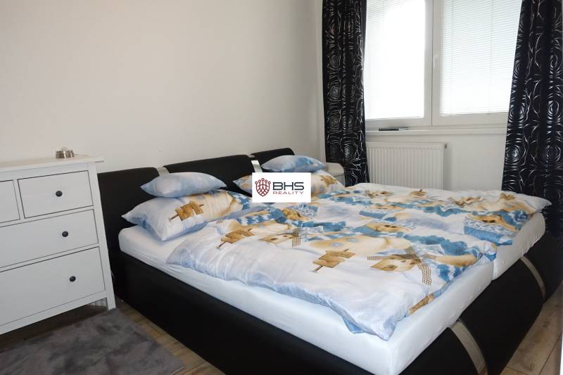 Bedroom in a 3-room apartment with a double bed, dresser, and window with black curtains.