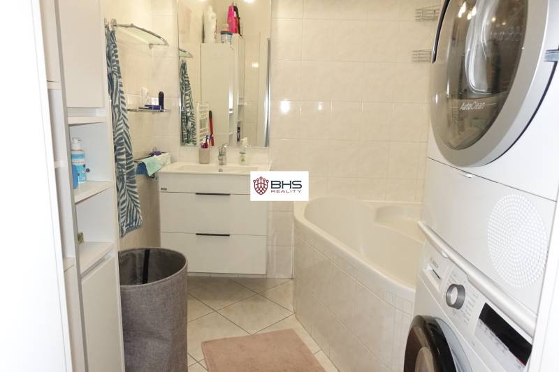 A bathroom in a 3-room apartment with a bathtub, sink, washing machine, and dryer.