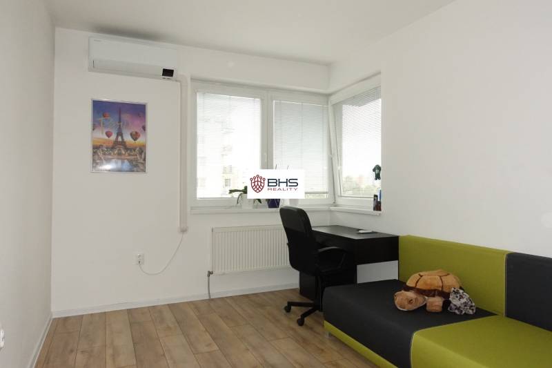 A room with a desk, chair, sofa, turtle, and air conditioning in a 3-room apartment.