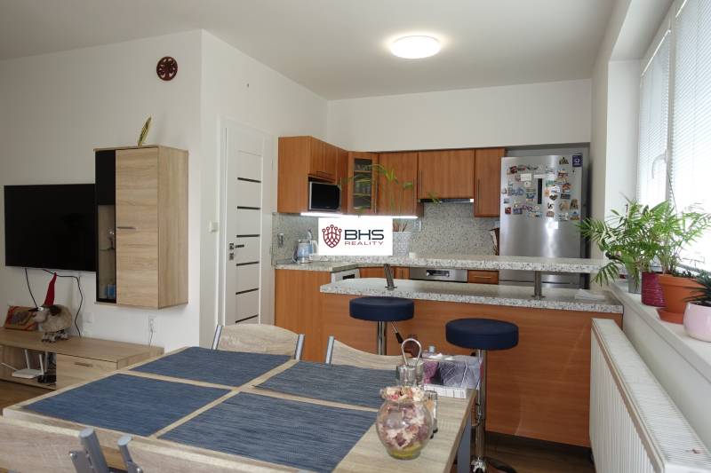 A kitchen in a 3-room apartment with wooden cabinets and a dining table.