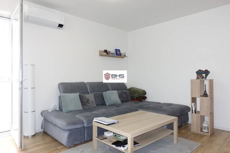 Living room in a 3-room apartment with a comfortable sofa, a shelf, and a wooden table.