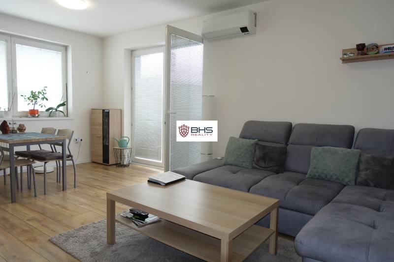 Living room in a three-room apartment with a comfortable sofa, coffee table, and dining table.