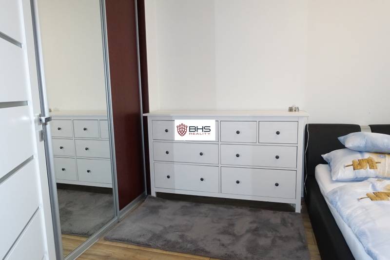 A room with a chest of drawers, a bed, and a mirrored wardrobe in a 3-room apartment.