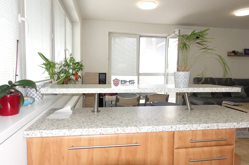 A kitchen unit in a 3-room apartment with indoor plants and seating.