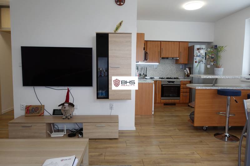 A kitchen with an island and a television in the living room of a 3-room apartment.