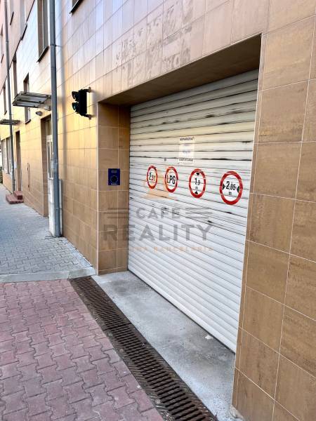A garage door on a building with safety markings; near a concrete sidewalk.