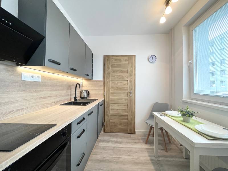 A modern kitchen in a studio apartment with wooden and metal elements, equipped with appliances.