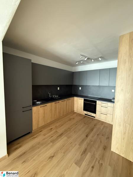 A kitchen in a 2-room apartment with a wooden floor and mixed cabinets.