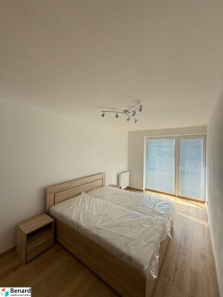A bedroom in a two-room apartment with a bed and a nightstand, a spacious window with blinds.