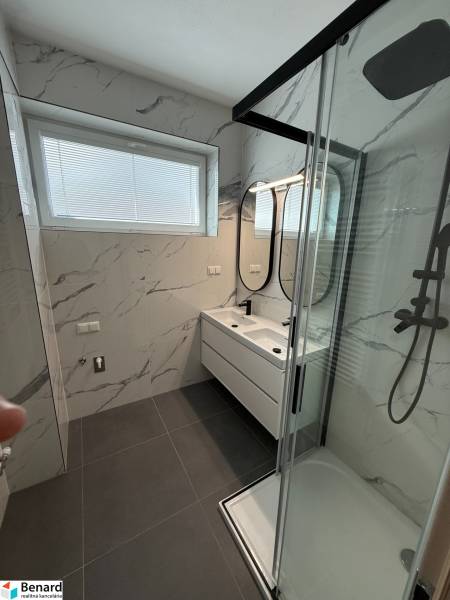 Bathroom in a 3-room apartment with white tiles and a glass shower enclosure.