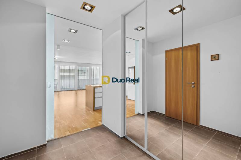 A hallway in a 3-room apartment with tiles, a mirrored wardrobe, and an entrance to the living room.