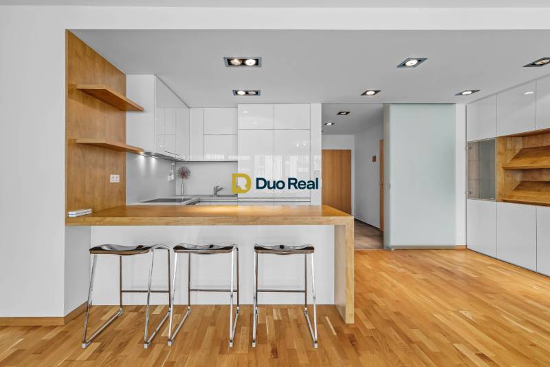 A kitchen in a 3-room apartment with a wooden bar counter and stools.