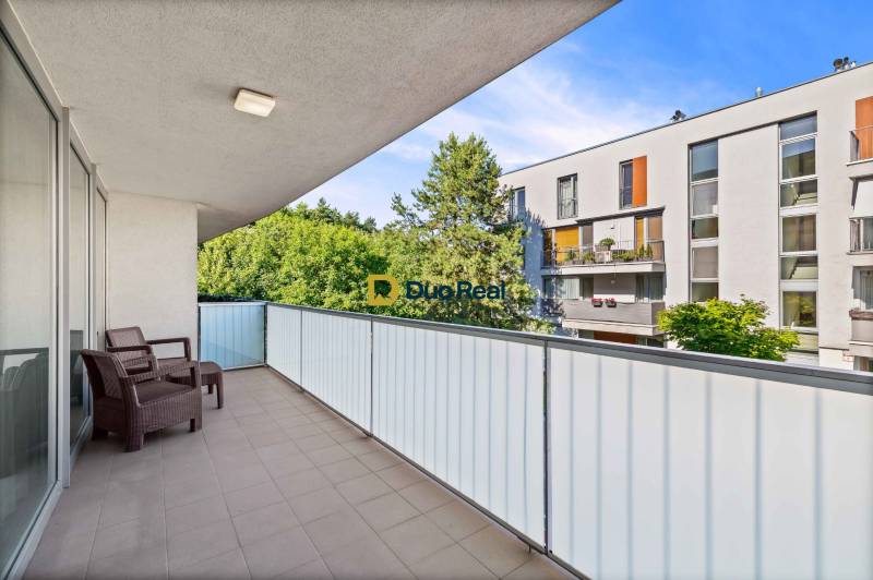 A spacious balcony in a 3-room apartment with a view of greenery and neighboring buildings.