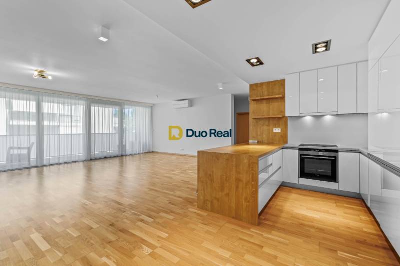 The bright kitchen with wooden flooring in the 3-room apartment has a spacious design.