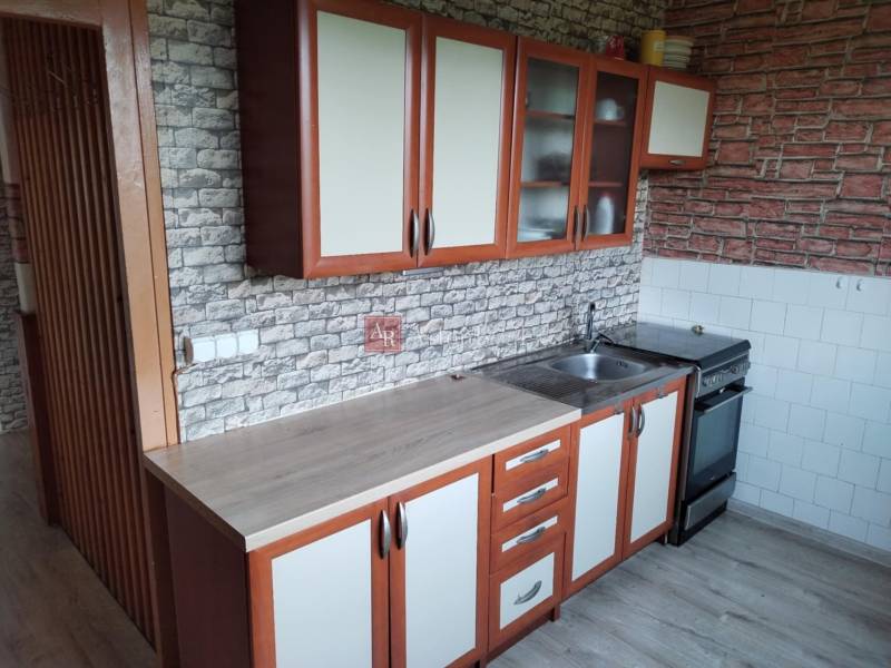 A kitchen in a 2-room apartment with cabinets and equipment, brick wall appearance.