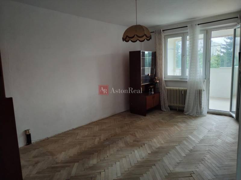 Living room in a two-room apartment with wooden flooring and access to a balcony.