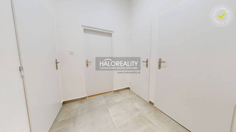 In the picture, there is a white door in an office space with a tiled floor.