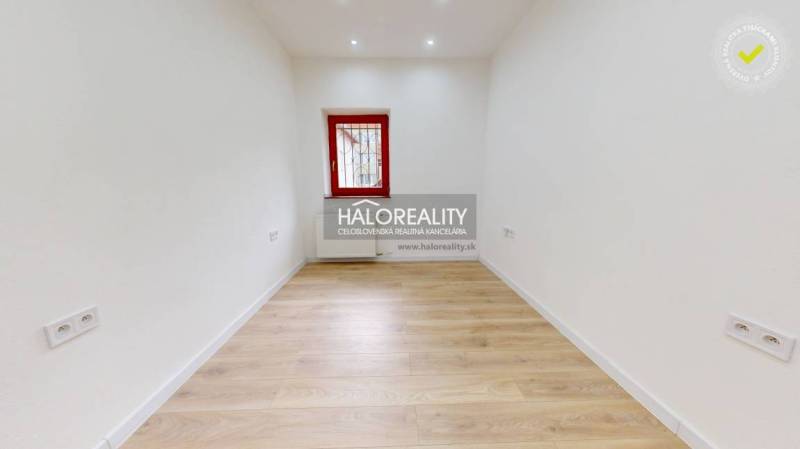An empty office space with wooden flooring and white walls.