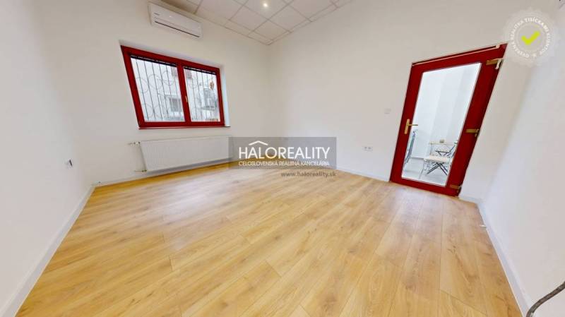 A room with a light wooden floor surface and red window frames in the offices.