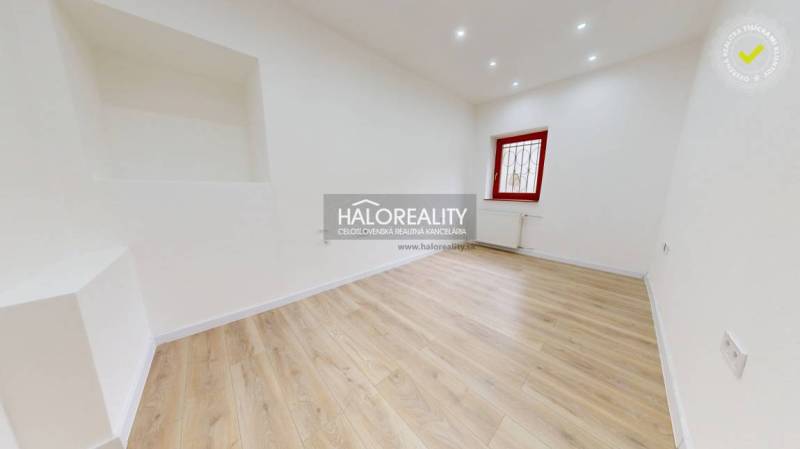 A bright office with wooden flooring and a red window frame.
