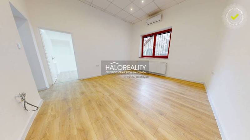 A bright room with laminate flooring and a large window in office spaces.