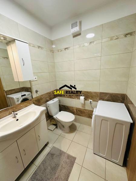 Bathroom with a washing machine and toilet in a 2-room apartment, light tiles.