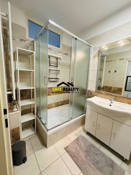 Bathroom of a 2-room apartment with a bathtub, sink, and shelf.