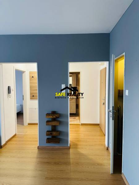 Interior of a 2-room apartment with wooden flooring and a blue wall.