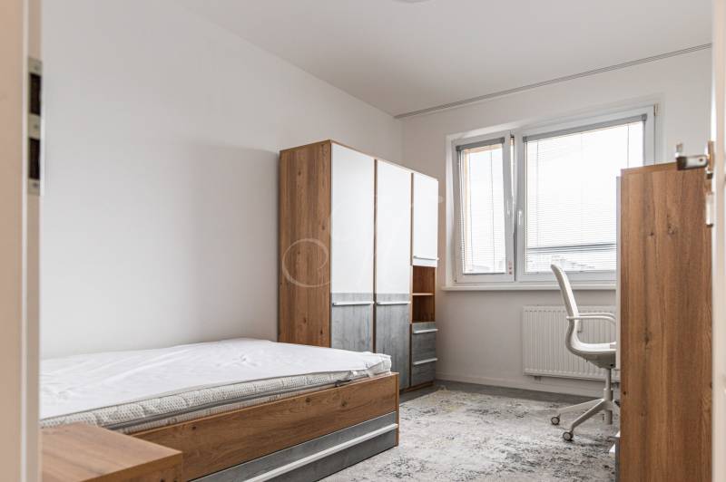 A room in a 3-room apartment with a bed, a wardrobe, and a desk with a chair.