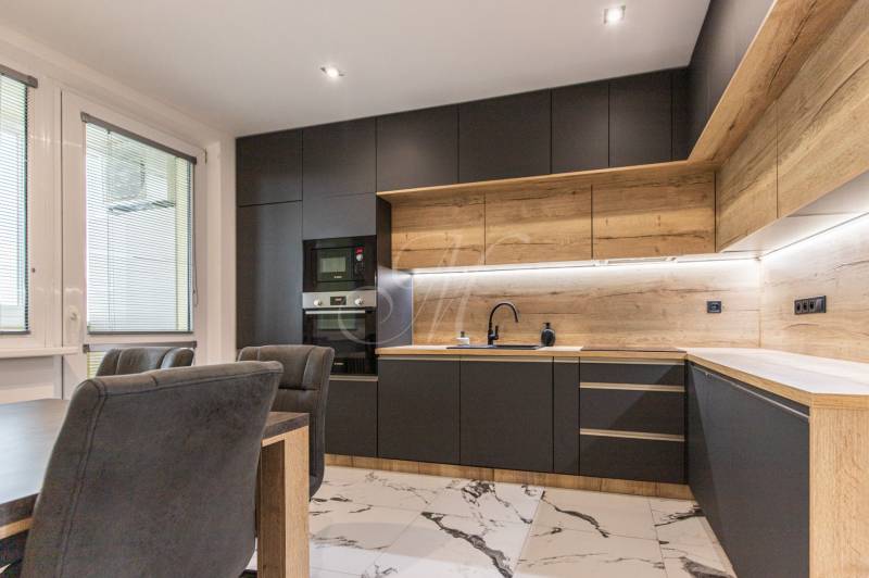 A kitchen in a 3-room apartment with wooden and black cabinets, marble floor.