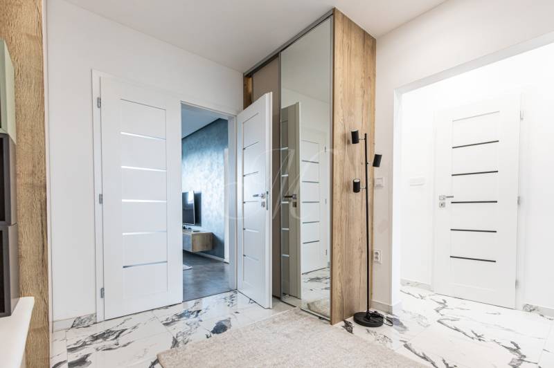 Hallway in a 3-room apartment with white doors and a large mirror.