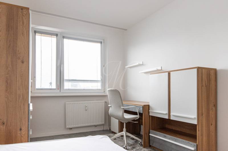 A desk with a chair and a cabinet in a 3-room apartment with white walls.