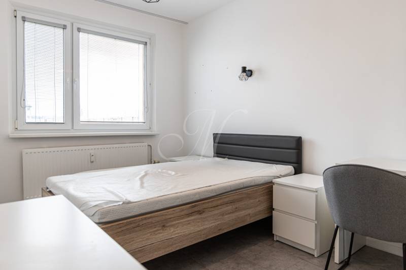 A bedroom with a bed and furniture in a 3-room apartment, light walls, a window with blinds.