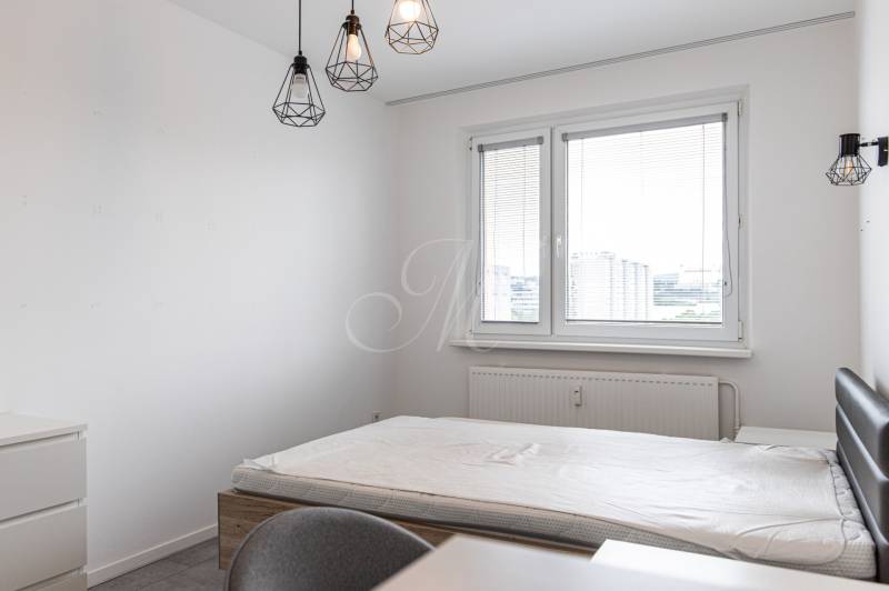 A bedroom with a bed, a desk, and hanging lamps in a 3-room apartment.