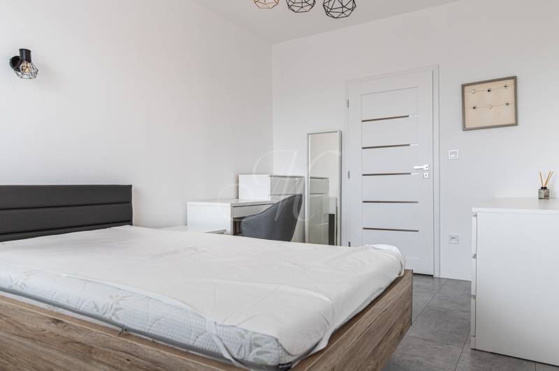 Bedroom in a 3-room apartment with a bed, table, and chair, in light shades.