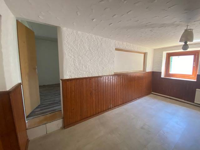 A room with wooden paneling and a window, part of apartment construction.