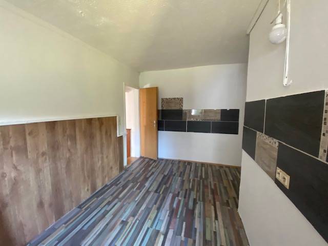 A room with wooden paneling and tiles on the wall, apartment construction.
