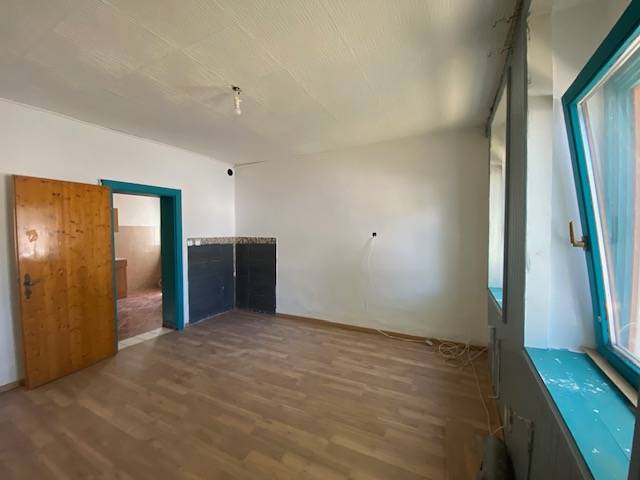 A room with a wooden floor, a window, and a door, suitable for apartment construction.