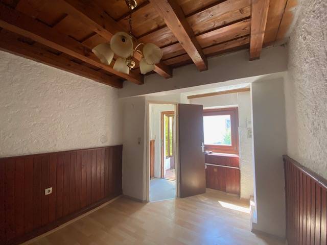 Construction of apartments with wooden paneling, light walls, and a ceiling with beams.